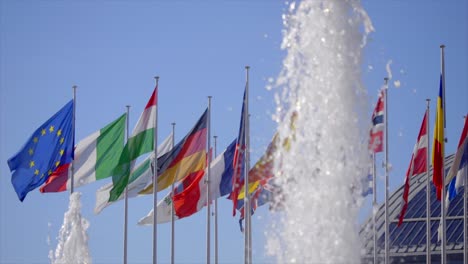 water fountain in front of waving displays of european national flags slow motion