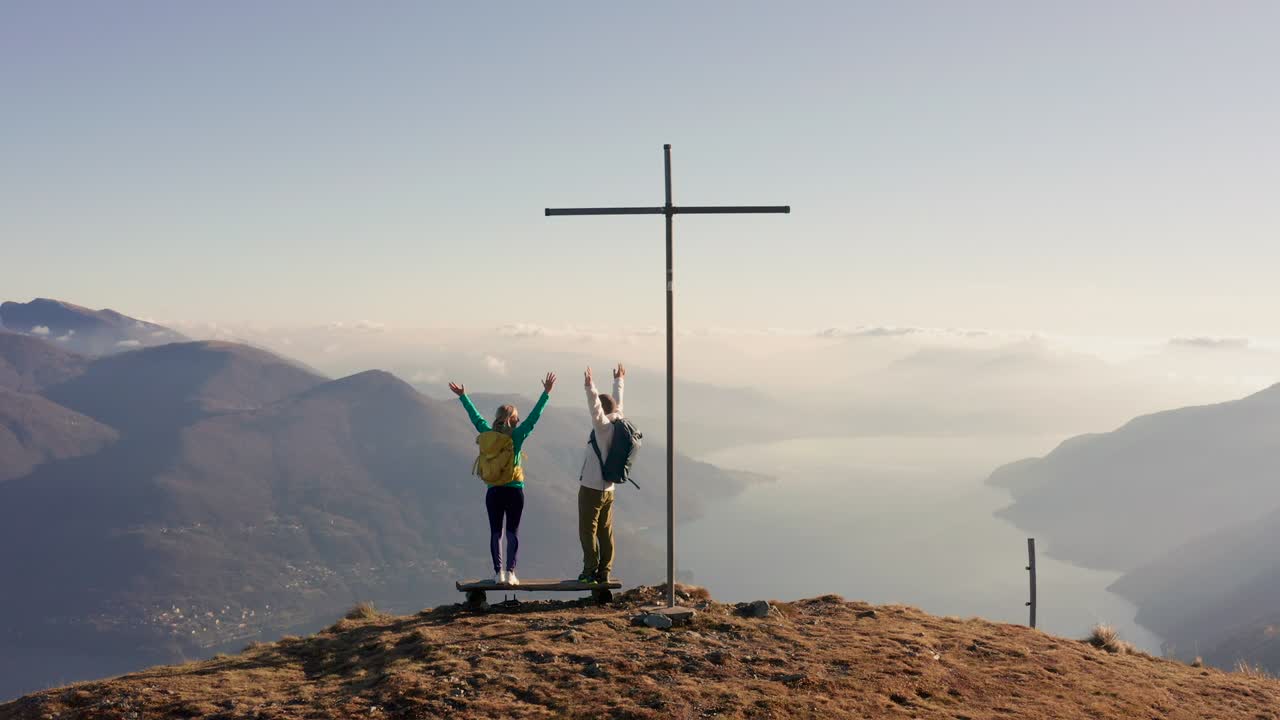 공중: 커플 하이킹은 산 꼭대기에 팔을 넓게 펴고 서 있습니다.