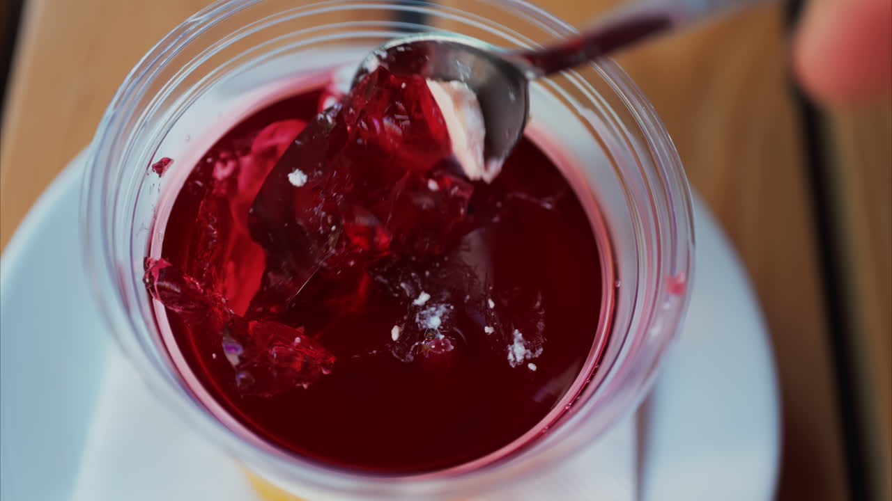 Close up of a spoon breaking into vibrant red jelly dessert
