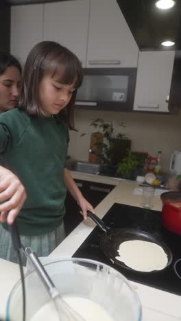 daughter and mother cooking pancakes