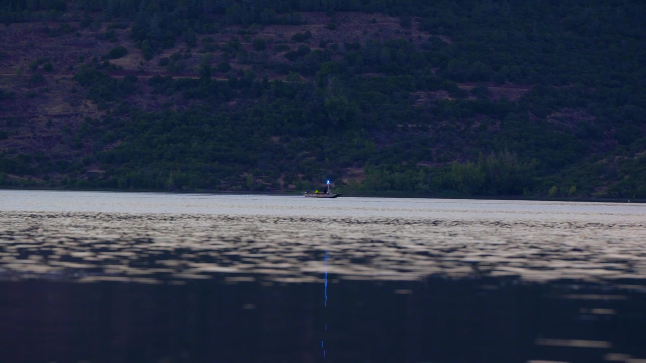 Båd lyser med et klart signalfyr over rolig sø i skumringen, kommunikation gennem enkle effektive metoder