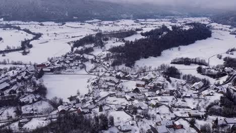 Fesselnde-Luftaufnahme-Eines-Malerischen-Slowenischen-Dorfes,-Das-Mit-Frischem-Winterschnee-Bedeckt-Ist