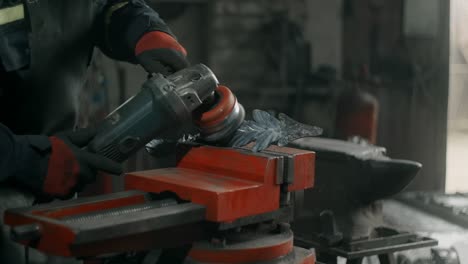 metalworker brushes steel with electric circular metal brush, metalwork in blacksmith's workshop, 4k 60p prores hq