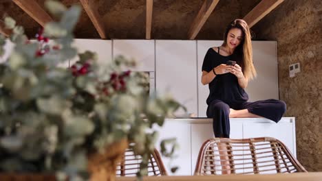 mujer navegando por internet en el teléfono inteligente en la cocina de la casa