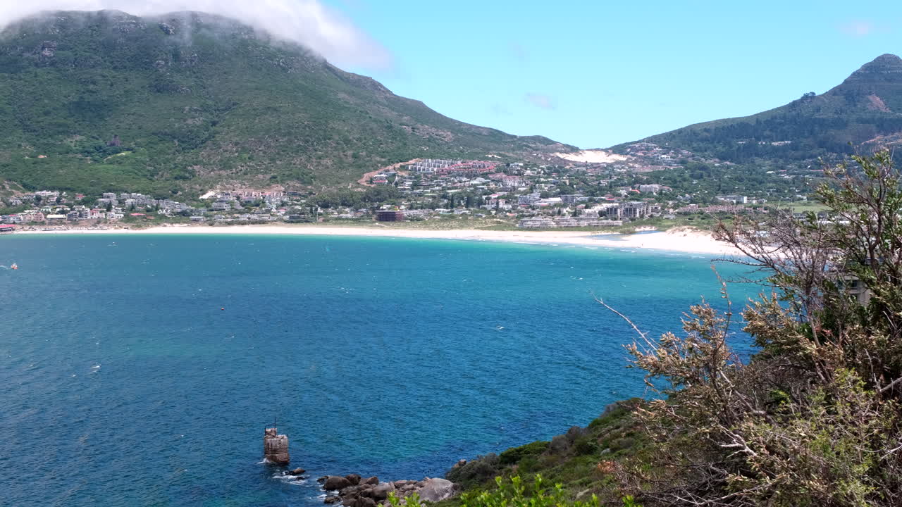Telephoto pan view over scenic Hout Bay from Chapman's Peak on windy day