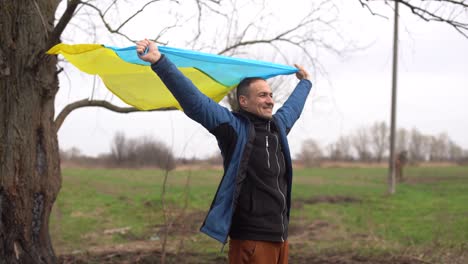 ukrainian man. young smiling man holding ukrainian flag. no war. support for ukraine. patriotic spirit rising hand of ukraine flag. freedom ukraine. nature background