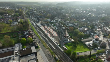 Aerial-orbit-shot-traffic-on-road-with-train-station-in-Wavre,-Belgium