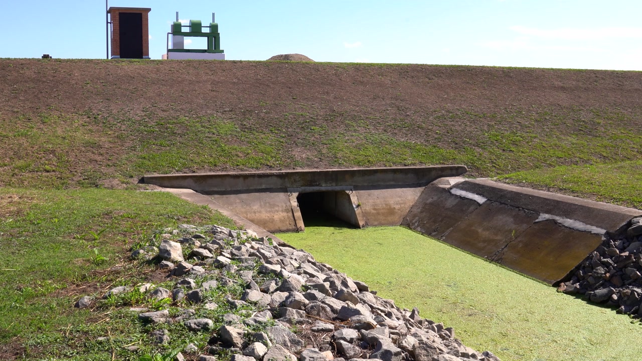 Concrete water management system with drainage canal, reservoir wall, and sluice gate
