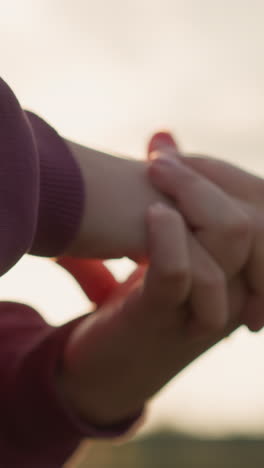 primer plano de la mano de la mujer con ropa marrón realizando una torsión de la muñeca con los dedos unidos, la luz del sol creando un efecto brillante alrededor de su mano