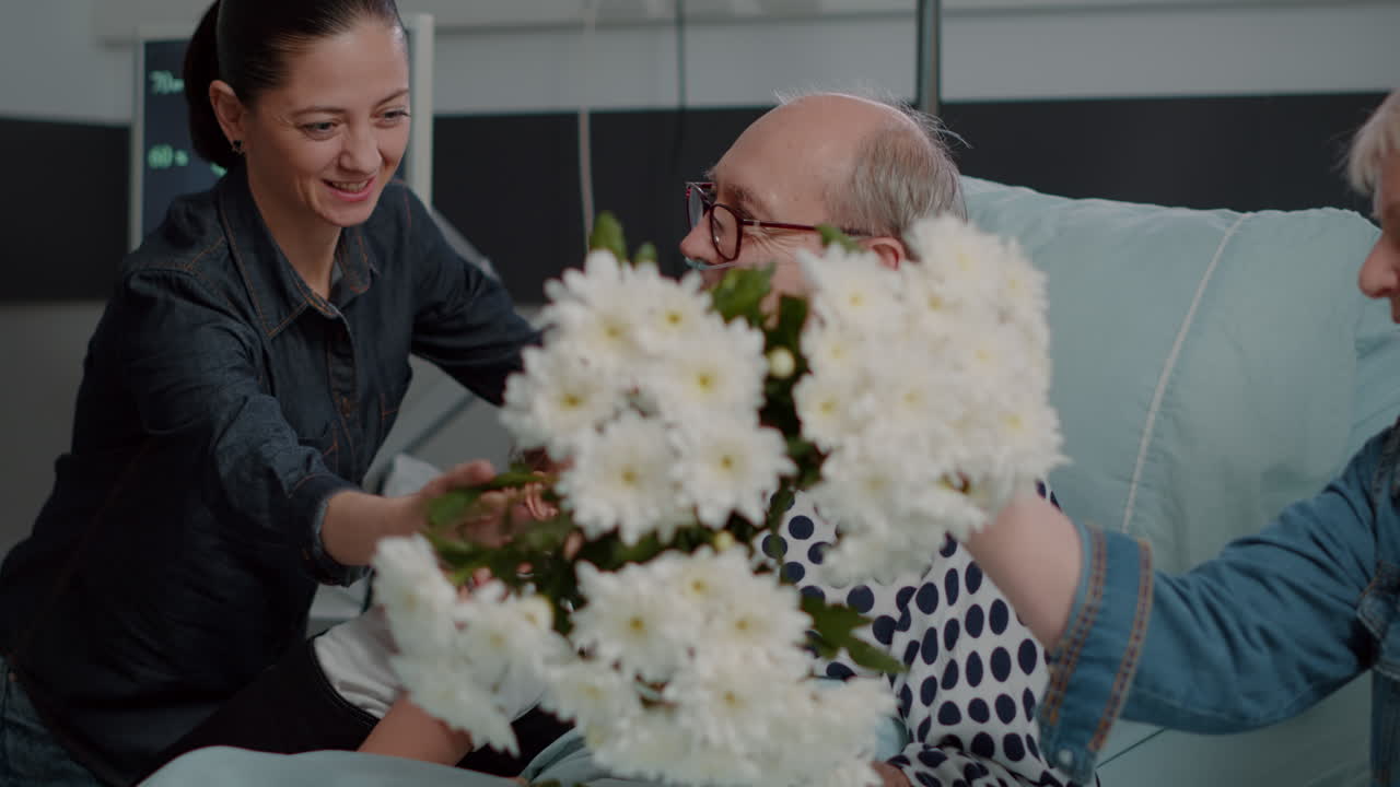 Close up of woman and child visiting retired man in hospital ward bed