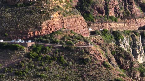 Autos-Passieren-Menschen,-Die-Die-Landschaftlich-Reizvolle-Route-Chapmans-Peak-Auf-Schmalen,-Geschwungenen-Klippen-Wandern