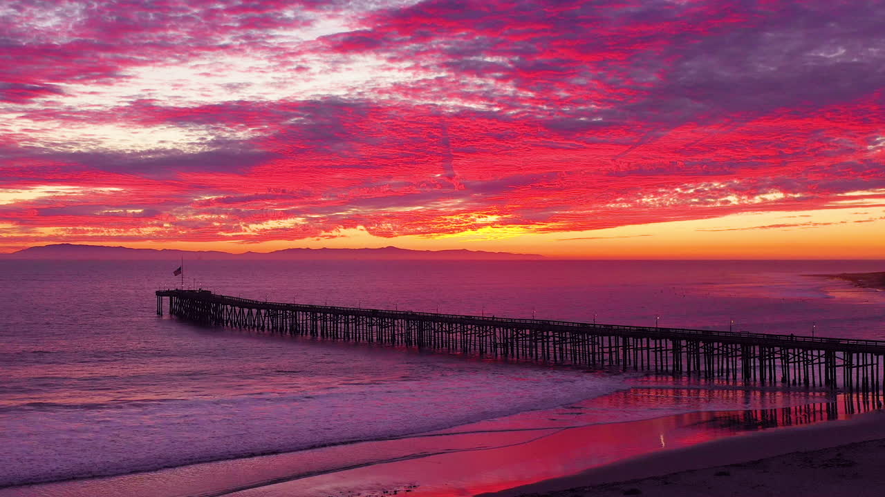 una asombrosa toma aérea de la puesta de sol sobre un largo muelle y el océano pacífico y las islas del canal en ventura sur de california 3