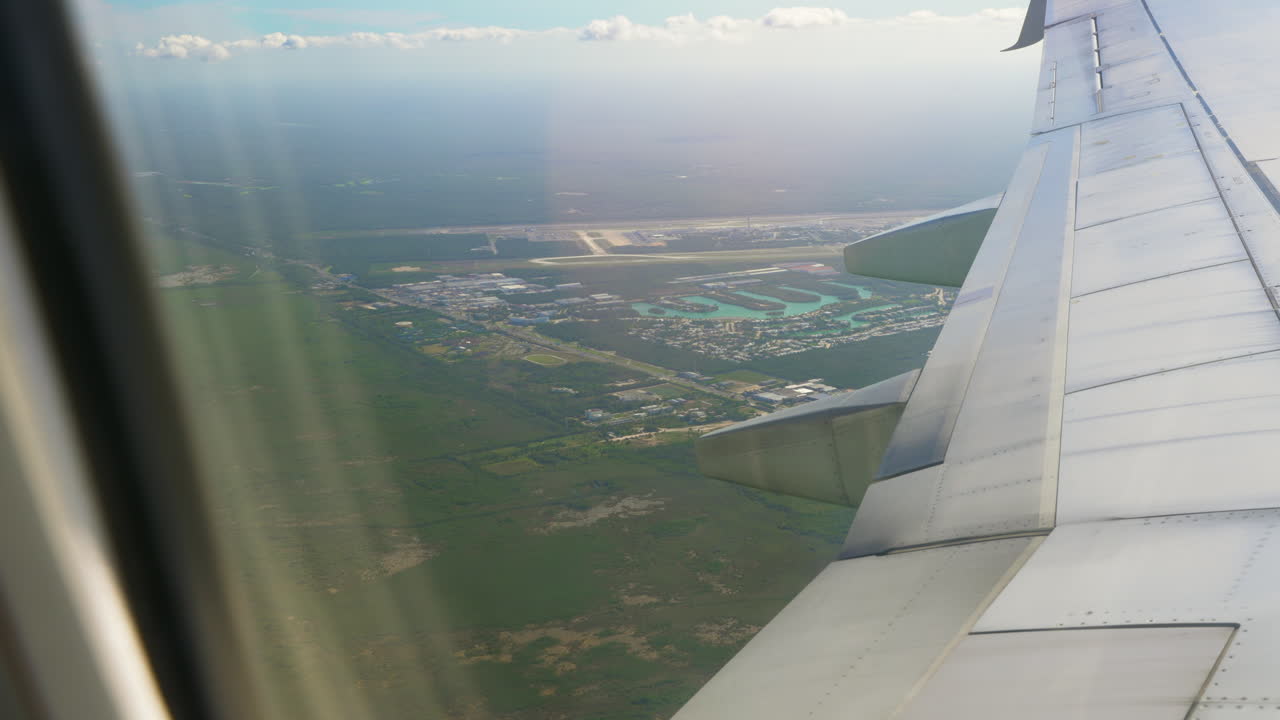 avión sobrevolando el aeropuerto internacional de cancún visto desde la ventana del pasajero con ala de avión en primer plano