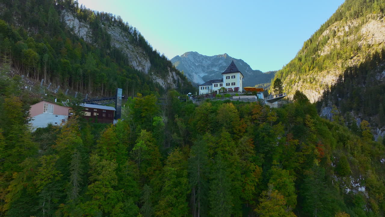 casa con techo puntiagudo en la cima de una colina en hallstatt - hermoso pueblo austriaco remoto en el valle entre montañas rocosas