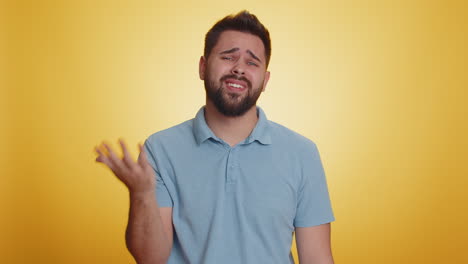 man with beard feeling sad and disappointed, looking at camera, yellow background