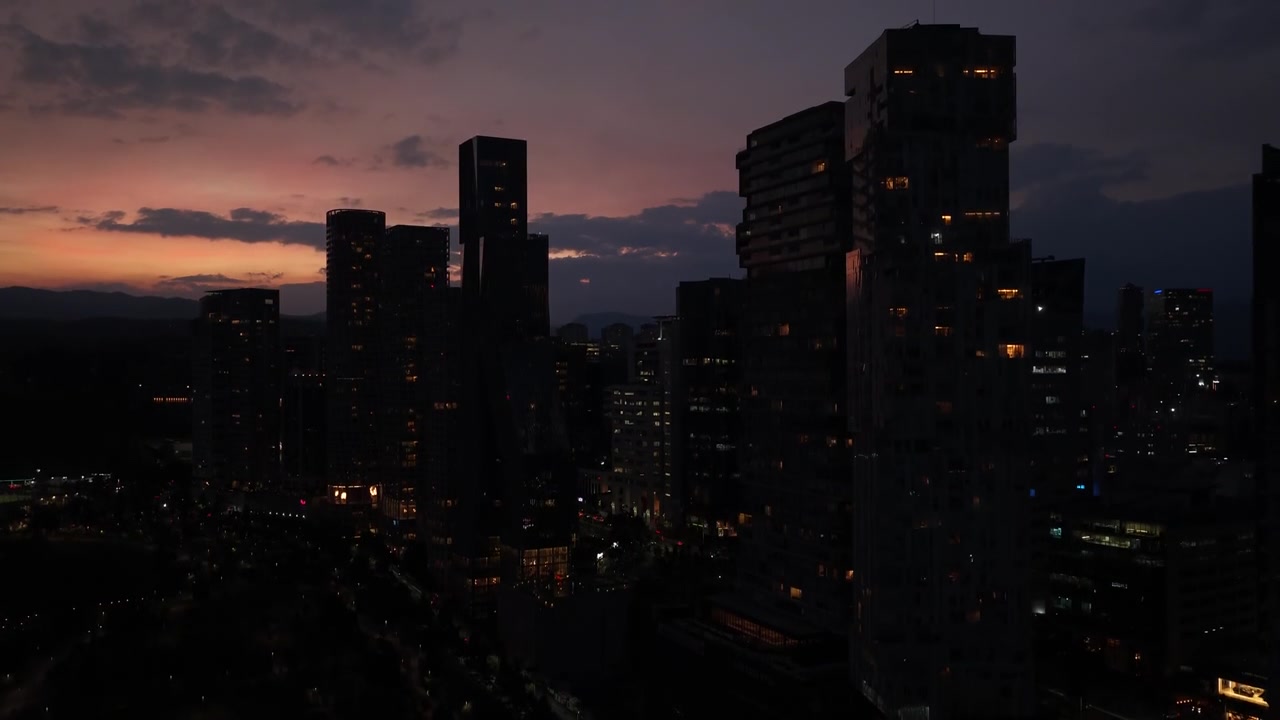 Dron ascendiendo frente al horizonte de Santa Fe al anochecer, rascacielos de la Ciudad de México y cielo colorido al atardecer