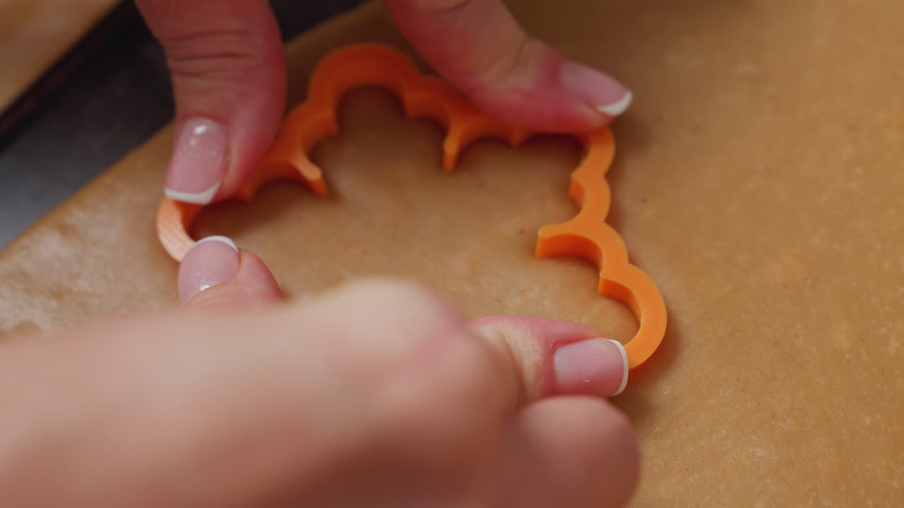 primer plano de un panadero usando un cortador de naranja para presionar la forma intrincada en una masa lisa, manos con uñas cuidadosamente cuidadosas aplican presión, asegurando un corte preciso
