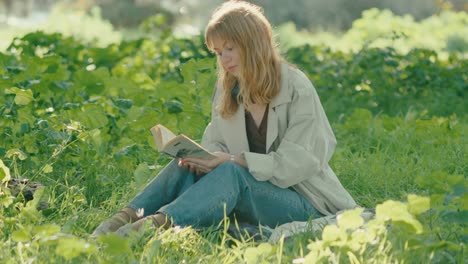 Tilt-down-toward-young-lady-sitting-in-lush-park-reading-a-book-om-summer-sun