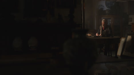 old passionate man writes a letter in his office at night