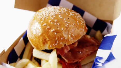 hamburger and french fries in a take away container on table