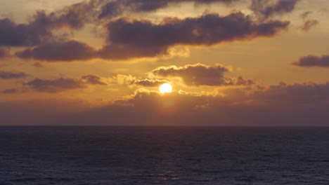 sunset over the ocean in estonia, with sun rays cascading through clouds, calm waters below
