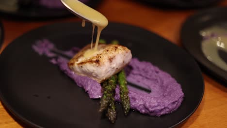 chef saucing a plate of fish with sweet potato mashed puree