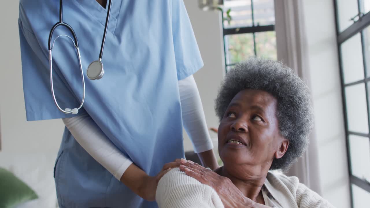Caring african american female doctor helping senior african american female