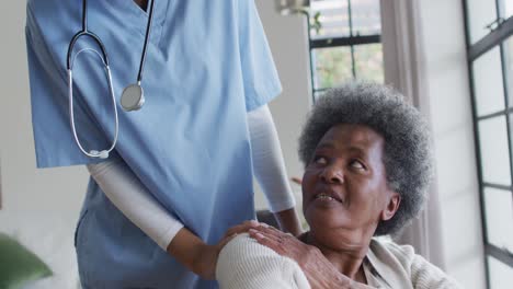 caring african american female doctor helping senior african american female