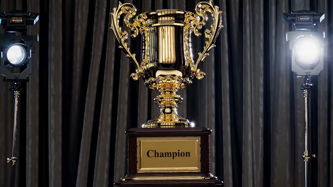 Una toma de video en ángulo contrapicado de un trofeo dorado con detalles ornamentados, flanqueado por luces de estudio