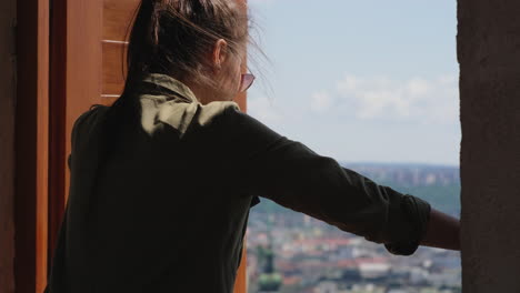 woman looking out a window at a city view