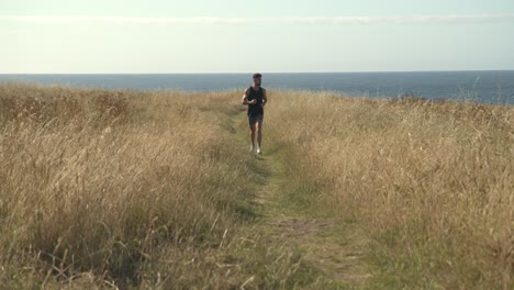 Man-running-along-path-at-seaside