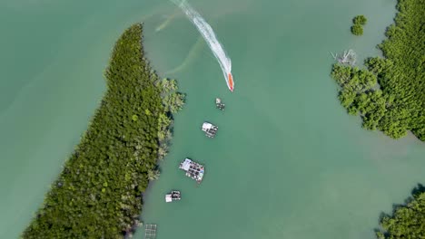 drone captures a boat navigating through phang nga bay, thailand, showcasing lush greenery and tranquil waters under bright daylight