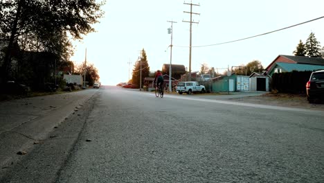 A-female-cyclist-riding-into-the-sunset-in-Tofino,-British-Columbia