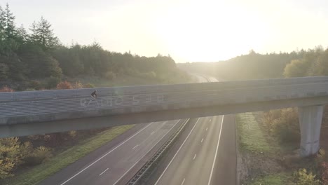 Drohne-Bei-Sonnenuntergang-Oder-Sonnenaufgang-Von-Mountainbikern,-Die-Auf-Einer-Überführung-Fahren