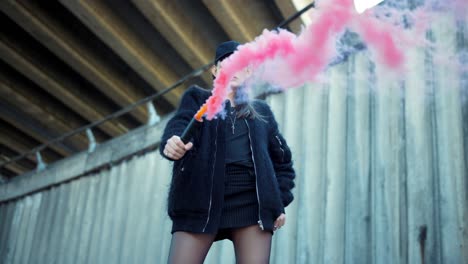 young woman posing at camera with colorful smoke bomb. girl protesting outdoors