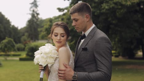 newlyweds, caucasian groom with bride walking, embracing, hugs in park, wedding couple