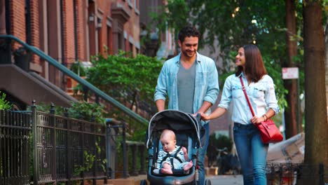 Couple-walking-in-street-with-baby-in-a-stroller,-close-up