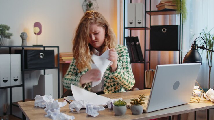 Angry furious businesswoman throwing crumpled paper nervous breakdown at office work losing temper