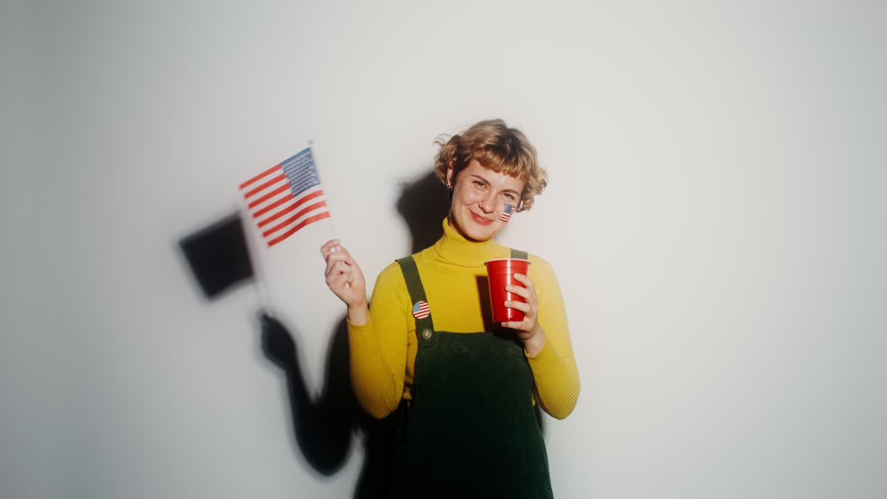 mujer sosteniendo una bandera estadounidense y una copa roja