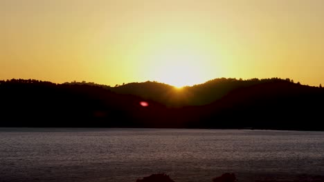 Zeitrafferaufnahme-Aus-Der-Luft,-Die-Bei-Sonnenuntergang-über-Einen-Einsamen-Fluss-Inmitten-Von-Bergen-Fährt