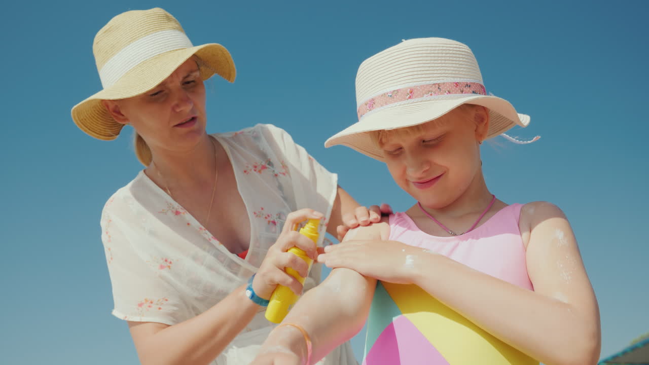 mamá pone protector solar en la piel de su hija descanso y protección solar