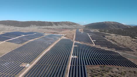 Drone-Sobre-Grandes-Paneles-Solares-Fotovoltaicos-En-Fila-Colinas-Rurales-Día-Soleado-En-Todo-El-Día
