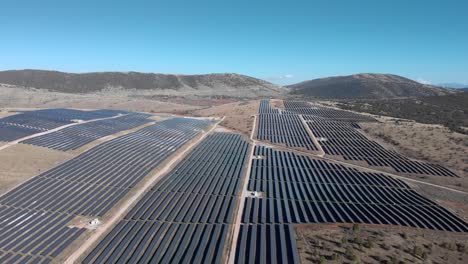 drone over big photovoltaic solar park panels in row rural hills sunny day wide