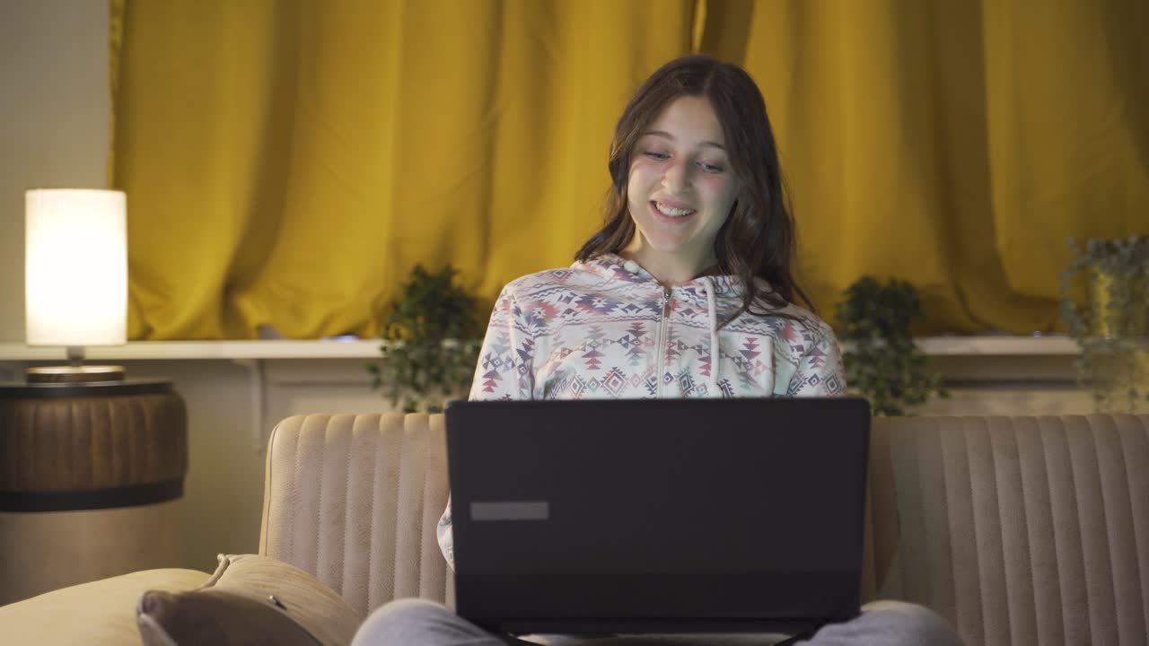 mujer joven viendo una película en el portátil por la noche en casa.