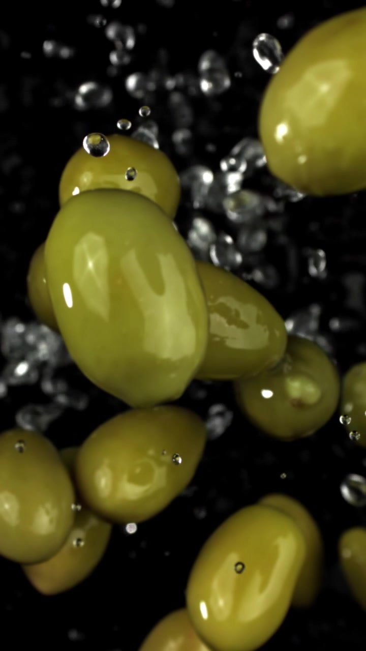 Olive verdi fresche che galleggiano nell'acqua con schizzi
