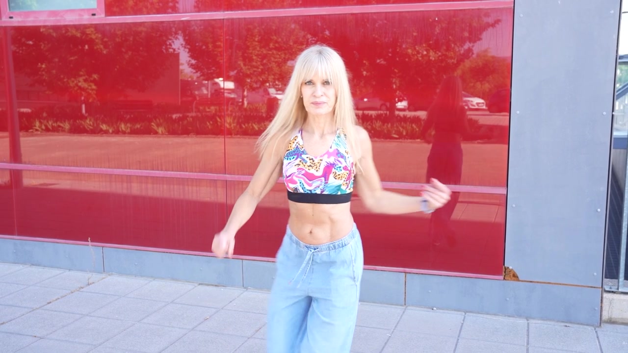 Una giovane donna con un abbigliamento casual balla gioiosamente all'aperto, irradiando gioia e libertà.