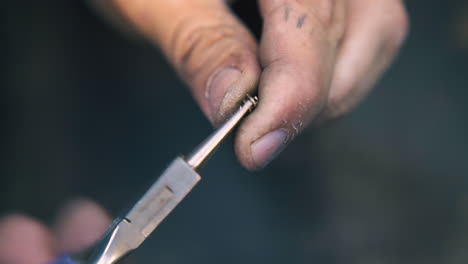 jeweler connects gold links to chain at workplace close view