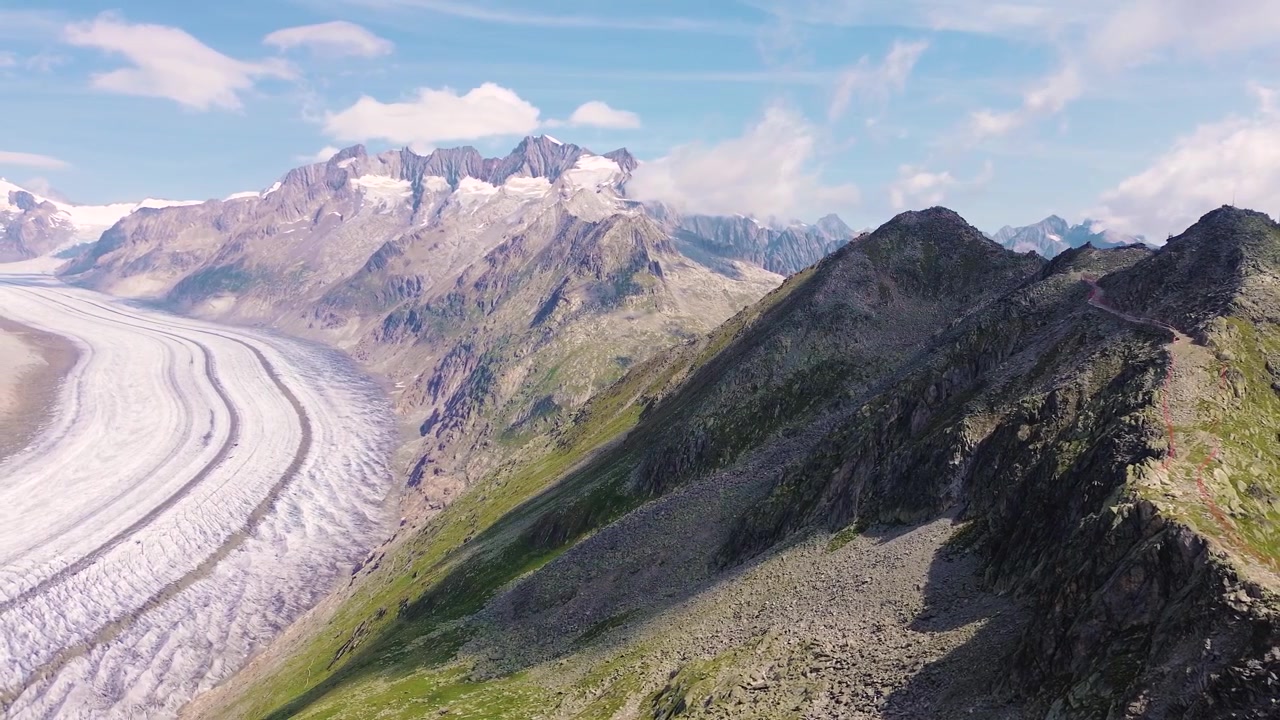 Vista aerea con drone del Grande Ghiacciaio dell'Aletsch circondato dalle Alpi Svizzere da una cima di montagna.