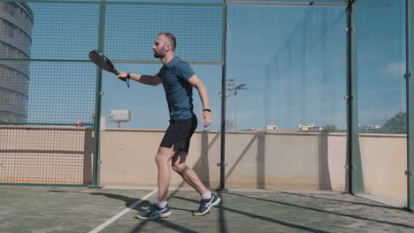 Padel-Tennisspieler-Macht-Einen-Niedrigen-Handback-Schlag,-Nachdem-Der-Ball-Die-Rückwand-Berührt