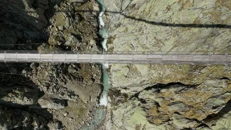 aerial overhead view of wooden swing bridge and natural flowing river in background